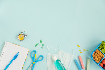 School the new reality global pandemic coronavirus covid-19 to school, tools, notebook, medicine mask, sanitizer, school lunch box  on blue background, stylish banner flyer, flat lay, top view