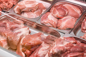 Heap of fresh meat food meat food background in supermarket store. Different types of raw meat in plastic boxes, leg of lamb on the bone, beef tail, beef neck, beef blade. Concept of farm and raw