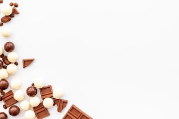 Candy background with chocolate on white table top view frame. Sweets desserts concept. Space for text