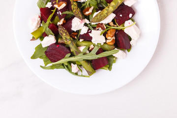 Green vegan salad with asparagus, feta, beetroot, arugula, lime and nuts