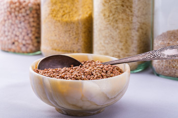 Raw dry buckwheat grain in a bowl with a spoon close-up.