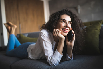 Young cheerful woman in couch talking on mobile phone