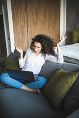 Obraz premium Amazed young woman looking at laptop screen, resting on sofa at home. Happy lady reading email with unbelievable news, win notification, feeling shocked surprised, sitting on couch in living room.
