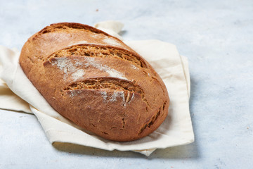Delicious loaf of artisan sourdough bread on rustic wood bench with blue cloth, top view, copy space