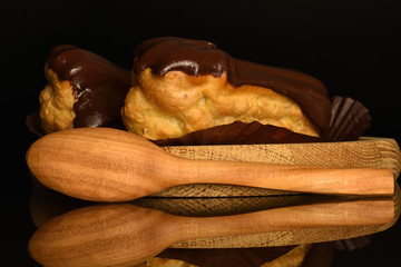 Sweet, mouth-watering chocolate eclairs, close-up, on a black background.