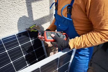 Man engineer installing solar photovoltaic panel system on roof of modern house. Electrician...