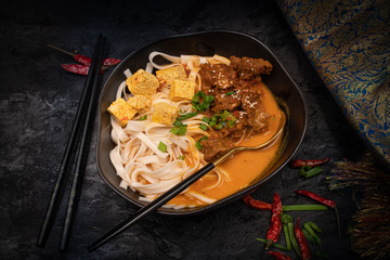 Vegan Thai rec curry with noodles, tofu and seitan served in black bowl