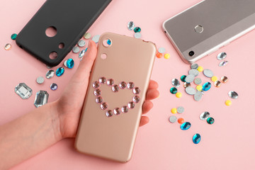 Girl put a rhinestone heart onto beige phone case