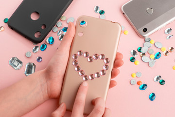 Girl putting pink rhinestones onto beige phone case