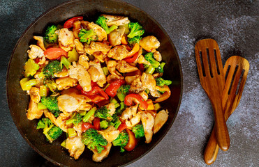 Stir-fried chicken with broccoli, bell pepper on dark background.