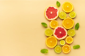 slices of grapefruit, orange, lime on a yellow surface top view