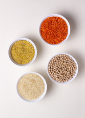 Rice, bulgur, lentils and chickpeas in white bowls on a white background. Cereals are a source of energy. Healthy food concept. Top view.