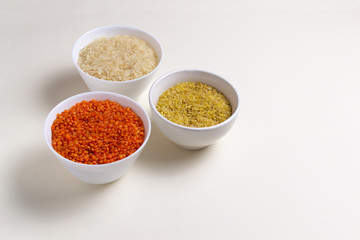 Rice, bulgur, lentils in white bowls on a white background. Cereals are a source of energy. Healthy food concept. Horizontal orientation. Copy space. Top view.