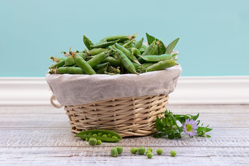 Fresh green peas in pods are in a braided basket