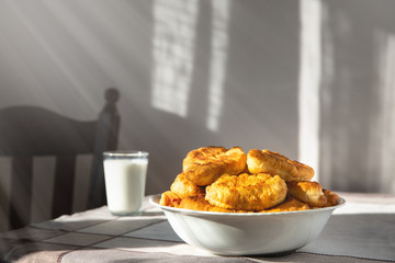 plate with fried pies on the table. Background blurred. Breakfast. Bakery products.near a glass of milk