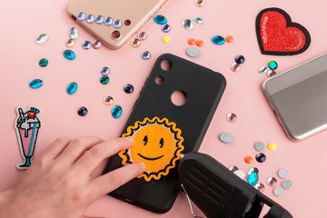 Girl putting a sun smile patch onto black phone case