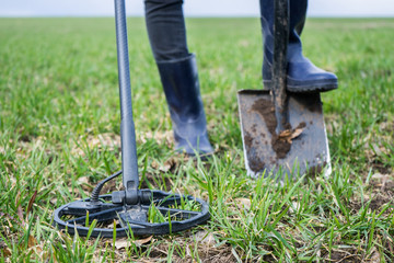 girl archaeologist or metal digger is looking for coins or metal with a metal detector. Search for precious old coins. Scrap metal collection. Girl in rubber boots with a tool for finding coins 