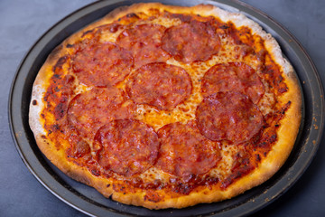 Pizza with chorizo sausage on a black background. Whole pizza. Close-up.