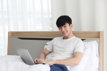 man using  laptop on bedroom ,  work from home. Technology and communication