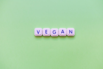 Vegan message made of letter game block over a bright green background.