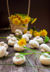 Champignons in a basket and yellow dandelions on a wooden rustic table