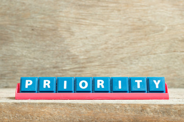 Tile letter on red rack in word priority on wood background