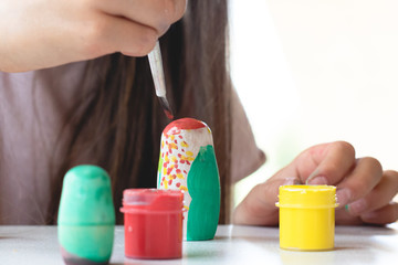 A child paints a wooden blank of a nesting doll. Children's crafts