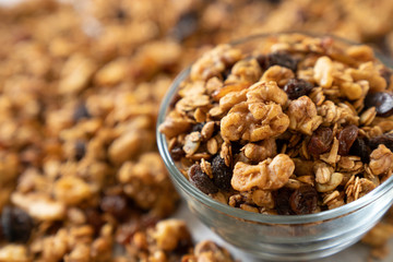 Healthy granola cereal with oats, pumpkin seeds, walnuts, and raisins in a glass bowl