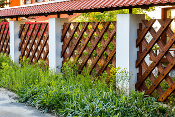 Dark decorative wooden fence to represent the protection of private territory. Tall grass near a...