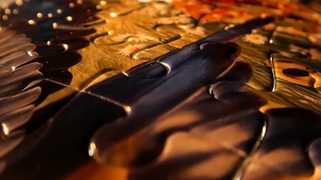 The camera moves slowly over of a colorful children's puzzle, the light is reflected from the rounded edges of the elements and reaching the place of the last missing link, it is installed and the puz