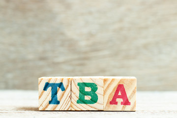 Alphabet letter in word TBA (abbreviation of to be announced) on wood background
