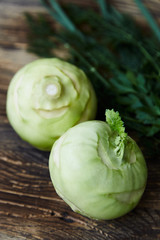 Two raw kohlrabies with some herbs (dill, parsley and chives) on a rustic wooden table. Healthy food. Vegan, diet.