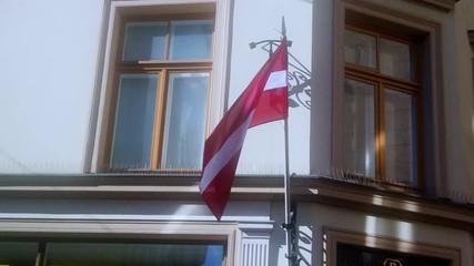 The Latvian flag flies in the wind at the corner of the building in the city Riga.