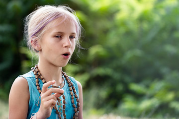 a cute teen girl with blonde hair chants a mantra on a rosary. Yoga, spirituality concept.