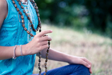a cute teen girl with blonde hair chants a mantra on a rosary. Yoga, spirituality concept.