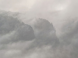 Obraz premium Spectacular aerial view of hilly silhouettes and misty valleys. Misty awaking of beautiful fairy valley.