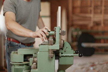 Man working in carpentry workshop. Machine assisted woodwork.
