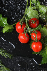 Vertical view of cherry tomato , greenery , red paprika close up under the water drops in a black background. Healthy diet. Vegetarian food