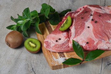 Raw pork meat, pork with kiwi fruit on a wooden cutting board
