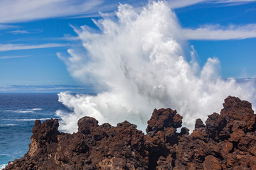 A big wave is crashing over a black rocks of volcanic coastline of Atlantic ocean on Tenerife island, Canary Islands, Spain