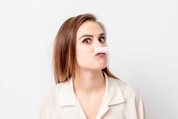 Young woman making mustache with sweet candy marshmallow on white background. Depilation and epilation concept.