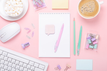 Woman office workplace with cup of coffee, notepad and stationery accessories on pink background. Top view