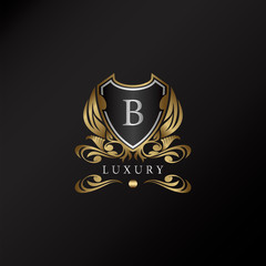 Obraz premium Shield logo in gold color with letter B Logo. Elegance logo vector template made of wide silver alphabet font on shield frame ornate style.