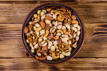 Various nuts (almond, cashew, hazelnut, pistachio, walnut) in ceramic plate on a wooden table. Vegetarian meal. Healthy eating concept. Top view