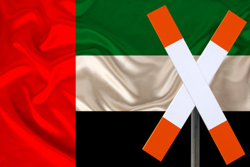 sign, stop, attention against the background of the silk national flag of the country of United Arab Emirates, concept of border and customs control, violation of state border, tourism restrictions