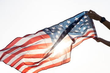 Young asian woman holding American flag with sun flare.