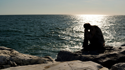 A woman silhouette watching sun on the beach at sunset
