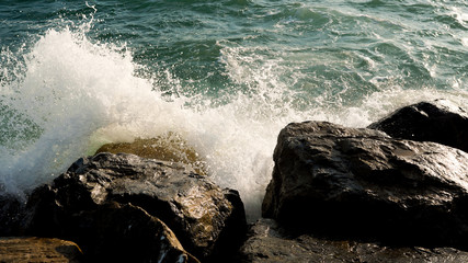 Waves crashing against rocks. Close up. Sunset.