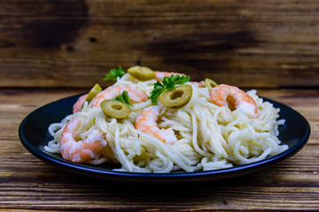Italian pasta with shrimps and olives in a black plate