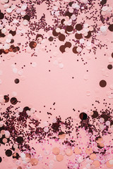 Pink celebration background with holiday sparkling confetti. Flat lay, top view